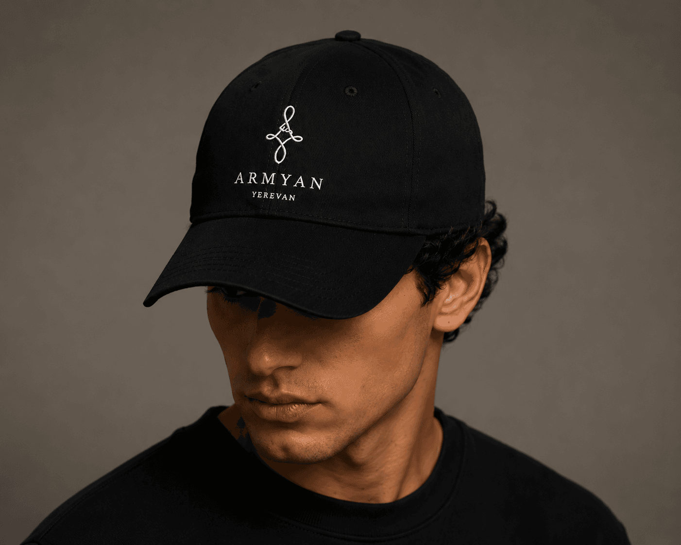 Model wearing ARMYAN black logo cap — studio campaign